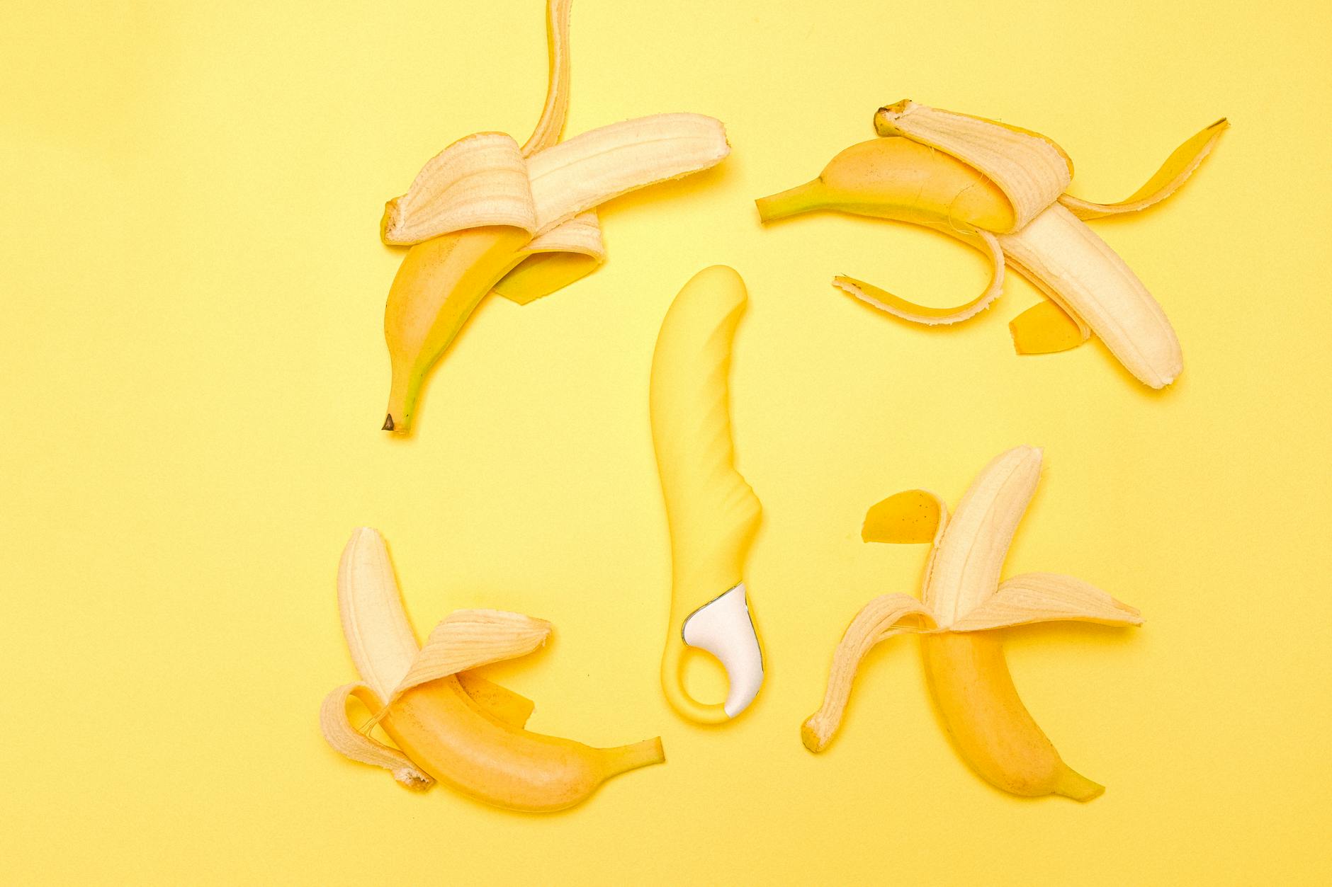 A yellow lemon vibrator surrounded by fresh lemons on a yellow background.