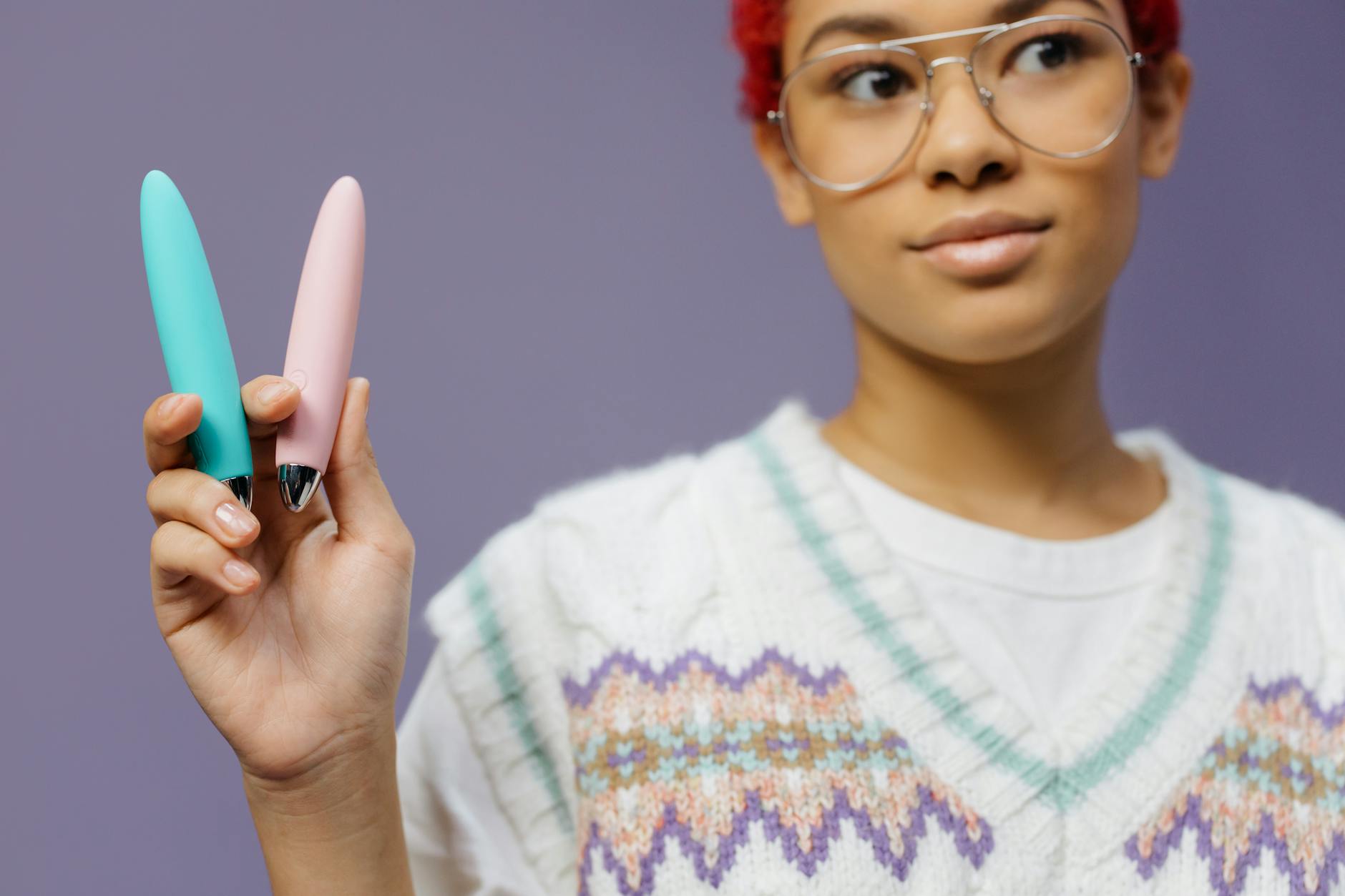 Two colorful vibrators held against a purple background, representing choice and self-care options