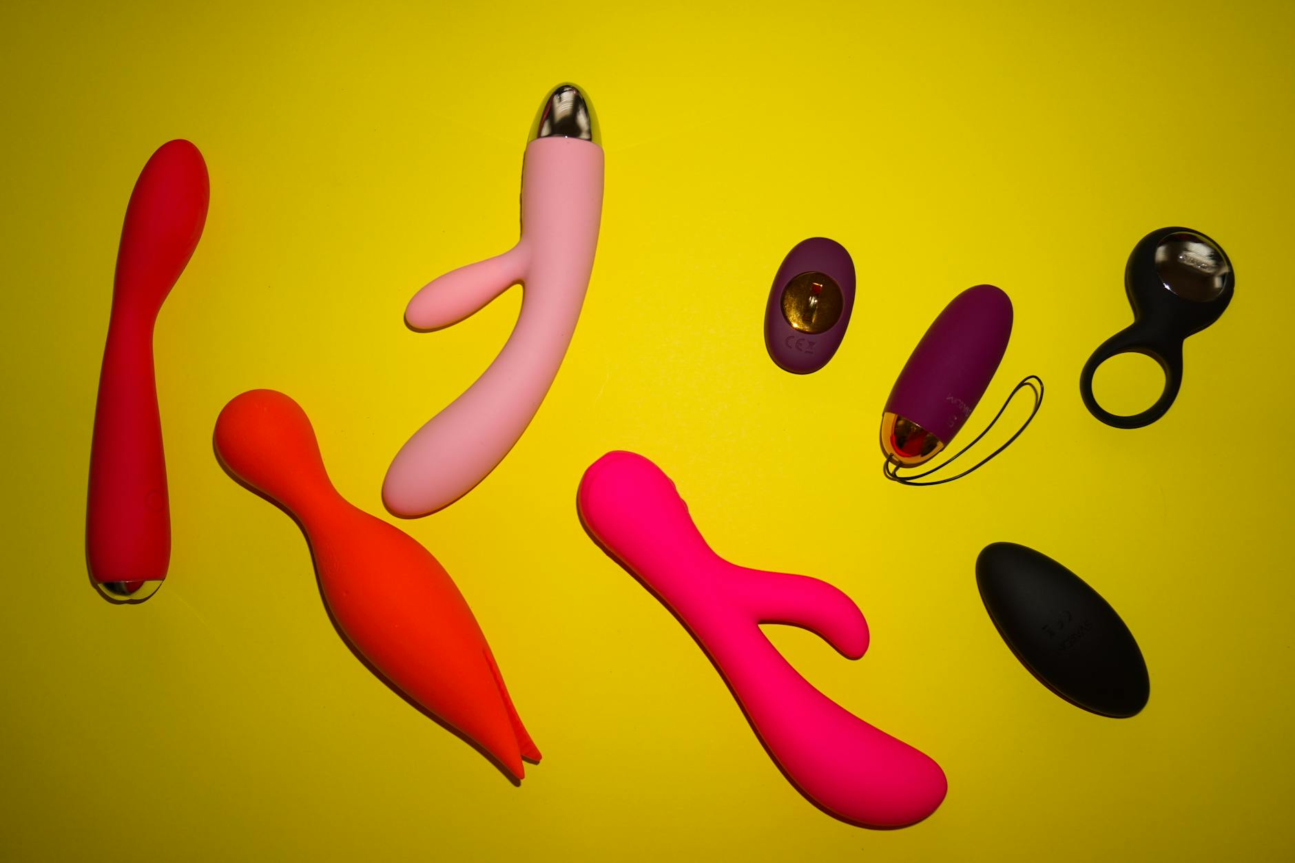Vibrant collection of lemon-colored and bright adult toys on a yellow surface, showcasing modern pleasure tools