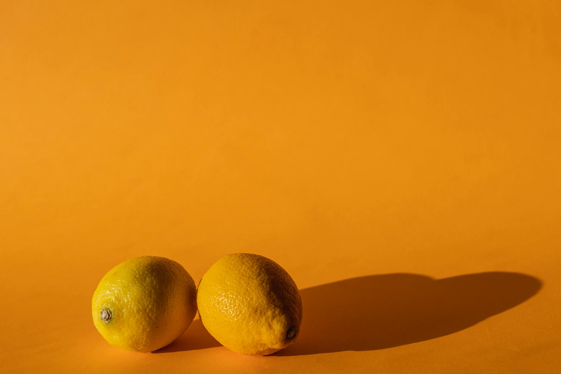 Fresh lemons arranged on a bright yellow background, symbolizing natural vitality and wellness
